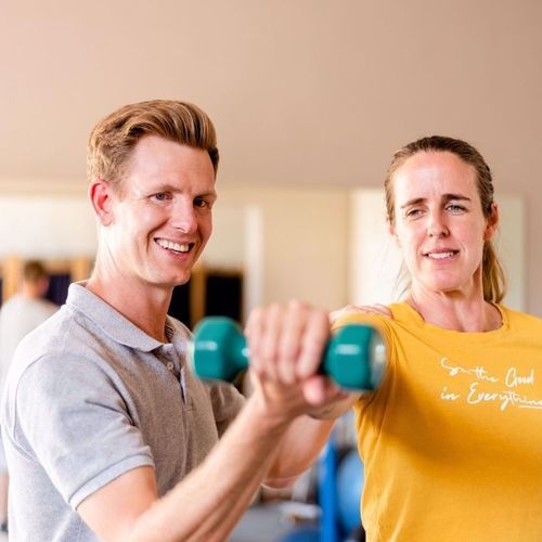 A woman lifting up a weight next to a man