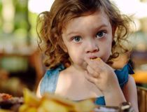 Young girl with curly brown hair eating some food