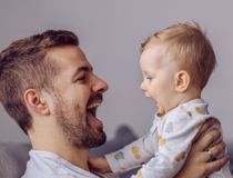 Man and baby facing each other and smiling with mouths wide open