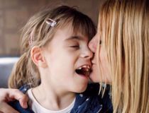 Mum kissing her daughter on the eye